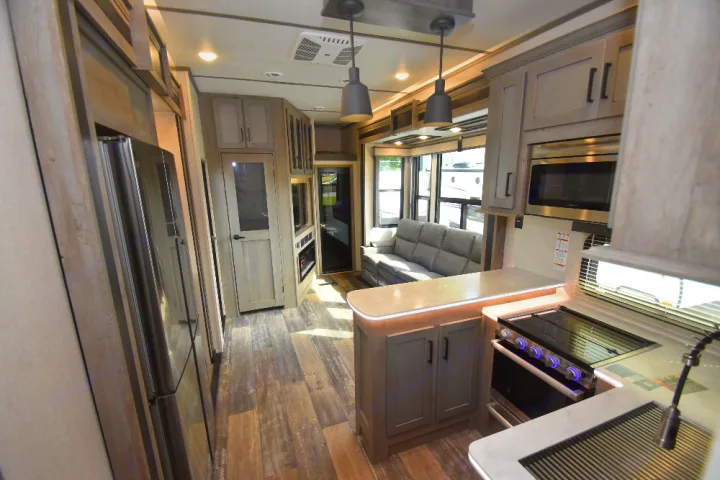 Step inside this luxury RV rental featuring a modern kitchen with an island, a cozy living area with a sofa, and bright, open spaces.. Keystone Raptor 2025