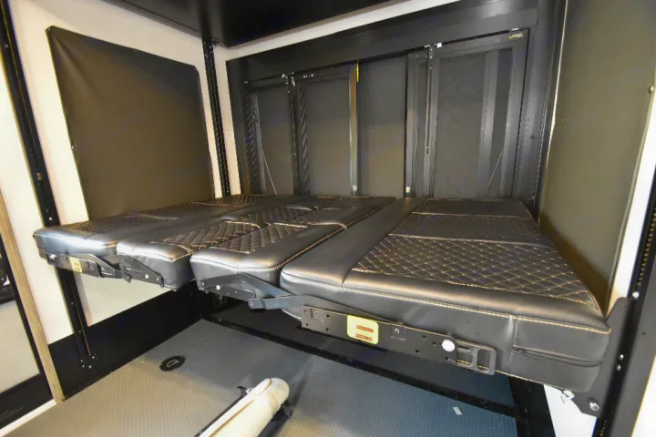RV interior featuring black quilted, adjustable beds/sofas in a garage area, ready for your next RV rental adventure.. Keystone Raptor 2025