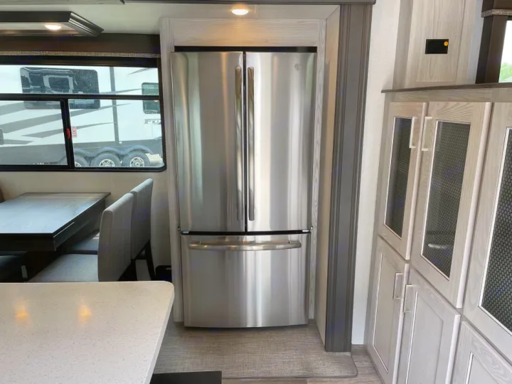 Spacious RV rental interior with modern kitchen featuring a stainless steel fridge, dining area, and stylish cabinets.. Keystone RV Montana High Country 2024