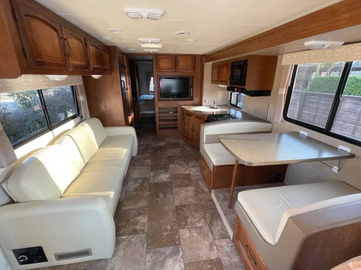 Spacious RV rental interior with living, dining, and kitchen areas, perfect for travel comfort.. Coachmen Mirada 2014