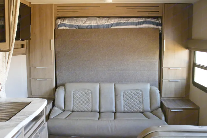 RV rental interior: A stylish grey sofa and a space-saving Murphy bed are ready for use in this compact living area.. Grand Design Imagine XLS 2021