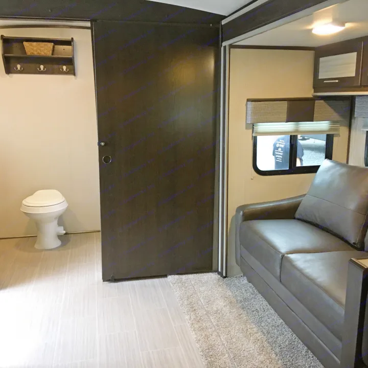 RV rental interior featuring a compact bathroom with a toilet, dark sliding door, and sofa living area.. Cruiser Rv Corp Fun Finder 2018