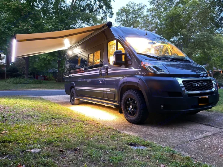 Outdoor shot w/ awning deployed and exterior lighting. Winnebago Travato 2021