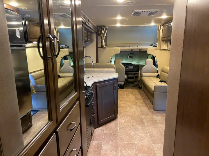 Inside an RV rental: a spacious interior with a tiled floor, full kitchen, comfortable dinette seating, and driver's cockpit.. Thor Motor Coach Chateau 2017