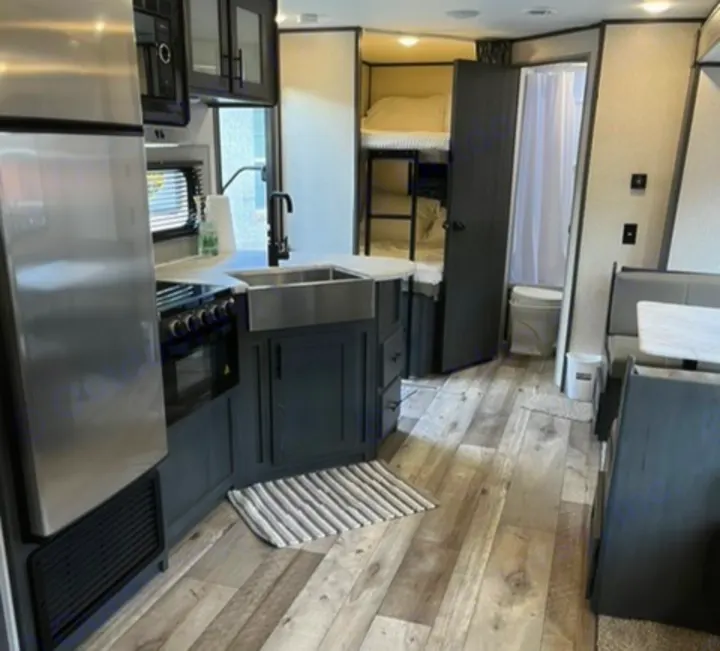 Spacious RV rental interior with modern kitchen, dining booth, bunk beds, and bathroom access. Ideal for comfortable travel.. Dutchmen Aspen Trail 2021