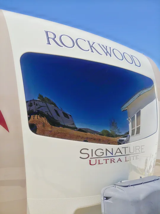 Rockwood Signature Ultra Lite RV rental front. Its reflective window mirrors another RV, house, and blue sky. Perfect for your trip!. Forest River Rockwood Signature Ultra Lite 2017