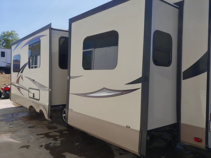A spacious beige RV rental with extended slide-outs, offering ample living space, parked on wet pavement.. Forest River Rockwood Signature Ultra Lite 2017