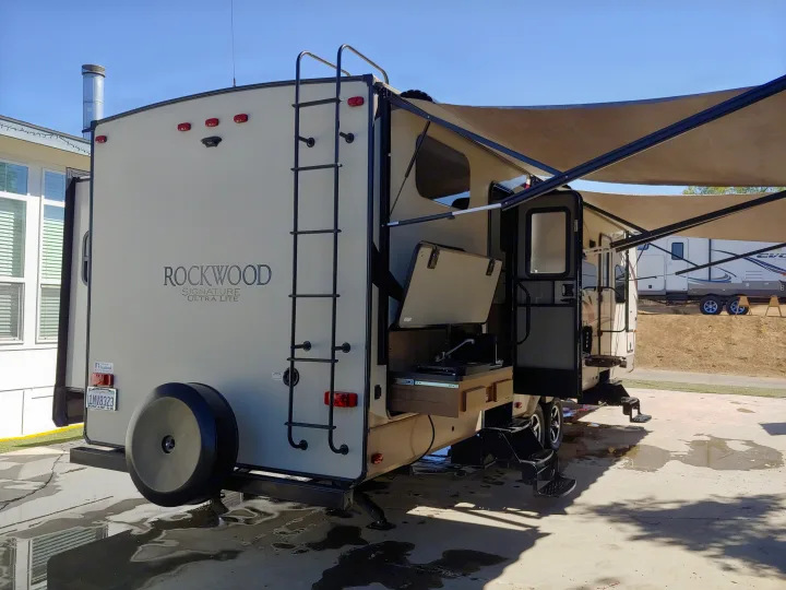 This RV rental features a rear ladder, outdoor kitchen, and extended awning, ideal for travel trailer camping trips.. Forest River Rockwood Signature Ultra Lite 2017