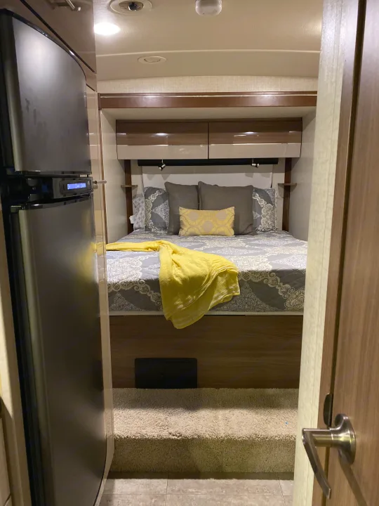 RV rental: Cozy bedroom features a bed with patterned bedding, overhead cabinets, and a vibrant yellow throw.. Winnebago View 2016