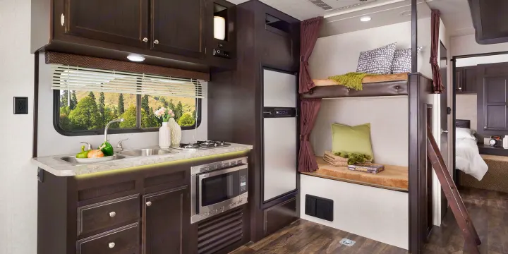 Step into this spacious RV rental featuring a well-equipped kitchen, cozy bunk beds with privacy curtains, and a private bedroom.. Jayco Octane 2017