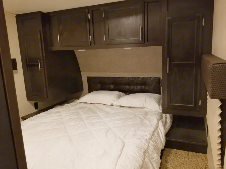 RV rental bedroom: cozy space with white bed, dark cabinets, and a textured black headboard.. Jayco Octane 2017