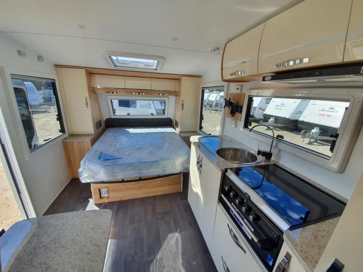 Spacious rv rental interior featuring a comfy bed, modern kitchenette, & large windows overlooking other caravans.. Avan Aspire 617 Family 2021