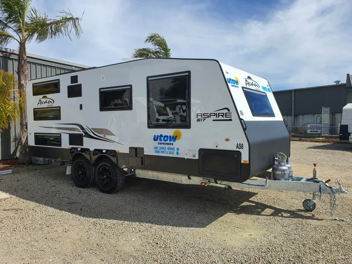 This white Avan Aspire 617 travel trailer is available for RV rental, sales, or service, displayed outdoors on a gravel lot.. Avan Aspire 617 Family 2021