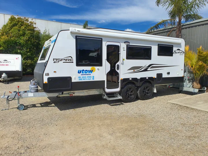 A sleek white Aspire 617 caravan with black trim, parked on gravel for RV rental & sales. Utow Caravans branding visible.. Avan Aspire 617 Family 2021