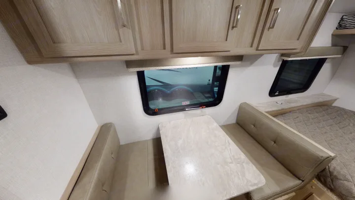 This RV rental interior features light wood cabinets, a comfortable dinette with a table, and a cozy bed area, perfect for travel trailer trips.. Forest River Other 2021