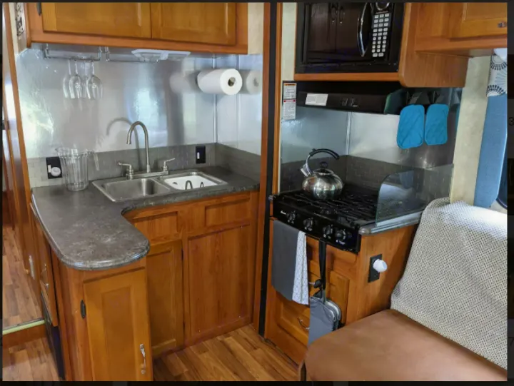 This RV rental features a well-equipped kitchen, including a sink, stove, microwave, and wooden cabinets.. Forest River Coachmen Freelander 2011