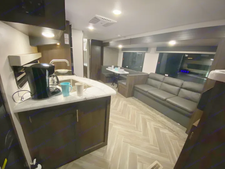 Spacious RV rental interior featuring a full kitchen, dining booth, and comfortable sofa area with modern decor.. K-Z Manufacturing Sportsmen 2021