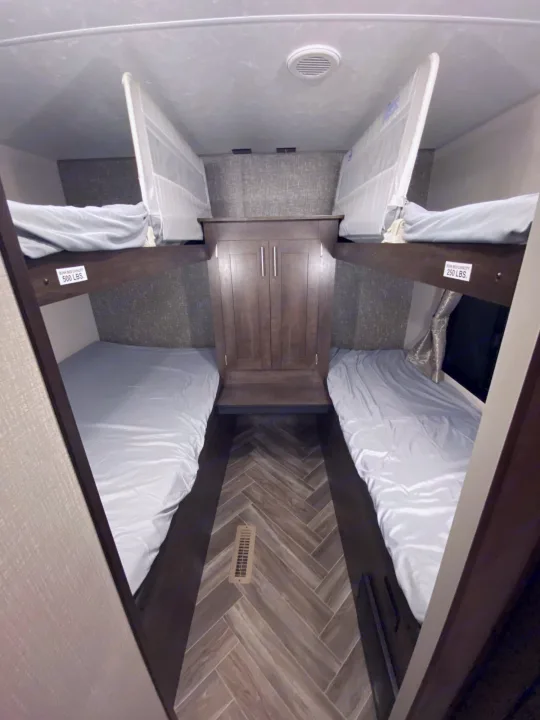 Inside this RV rental, find a comfortable sleeping area with four bunk beds. Two bunks on each side feature light sheets and safety nets.. K-Z Manufacturing Sportsmen 2021