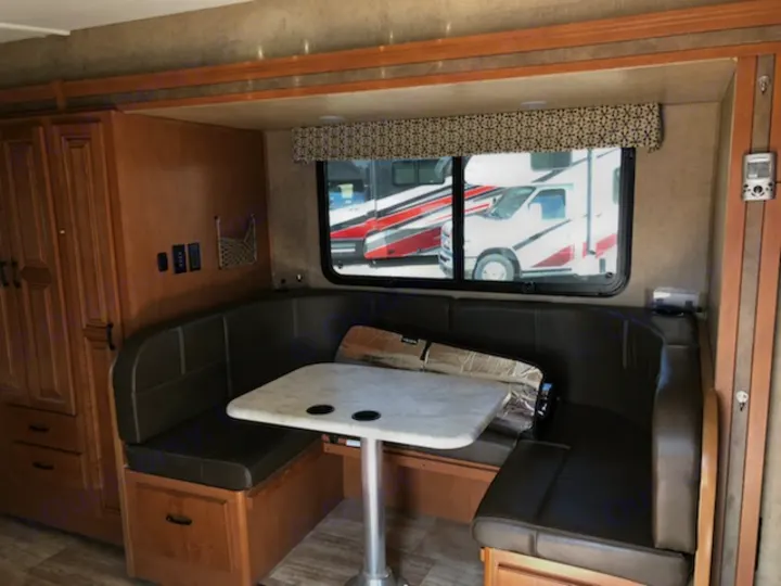 U-shaped dinette in an RV rental, featuring a table, comfortable seating, and window view. Ideal for meals & relaxing.. Forest River Sunseeker 2017