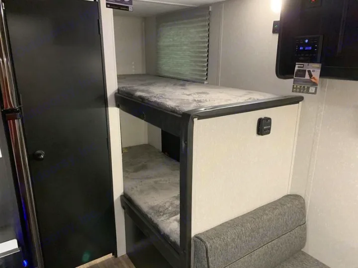 This RV rental bunkhouse features two cozy bunk beds, a lower seating area, and a black door, ideal for families.. Forest River Cherokee Wolf Pup 2022