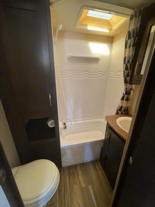 Compact RV rental bathroom featuring toilet, tub/shower combo, and sink with vanity.. Forest River Evo T2550 2019