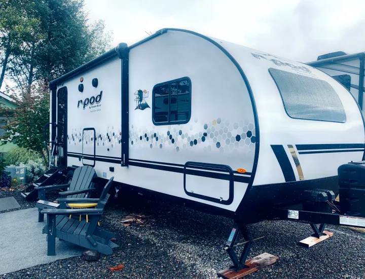 Stylish r-pod RV rental with unique honeycomb design, parked on gravel next to Adirondack chairs for camping.. Forest River R-Pod 202 2021