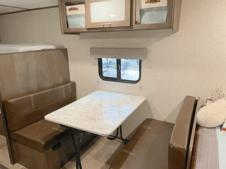 Cozy RV rental interior featuring a dinette, bunk bed, and overhead storage.. Coleman Other 2022