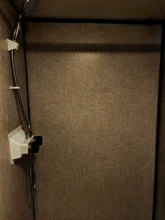 This RV rental shower features a compact, functional design with a handheld showerhead and textured walls.. Coleman Other 2022