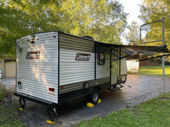 This Coleman RV rental, with its awning extended, is parked and stabilized on a paved driveway.. Coleman Other 2022