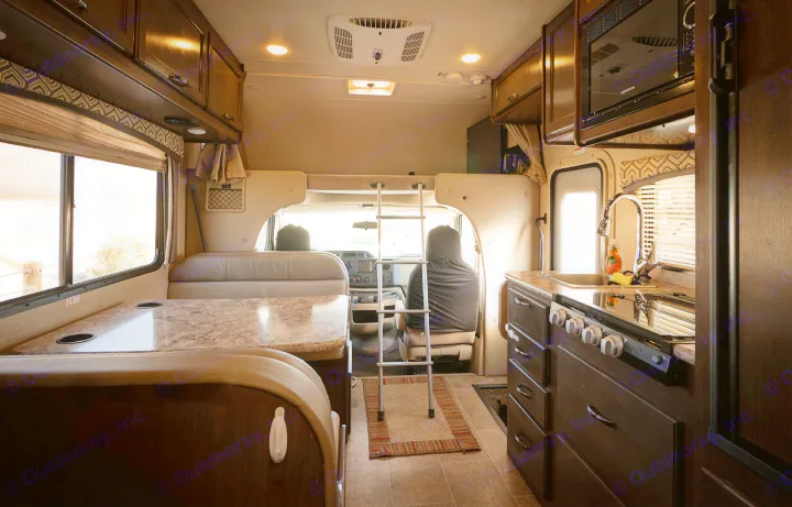 Interior of an RV rental, showing the kitchen on the right, dining area on the left, and bunk overhead.. Thor Motor Coach Chateau 2019