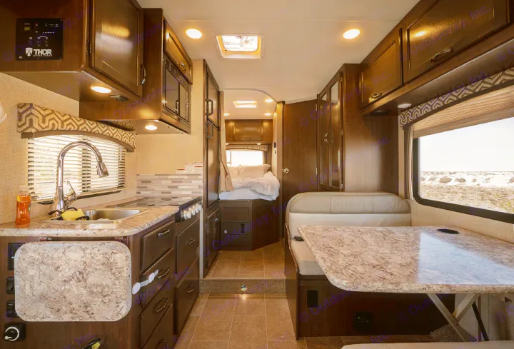 Spacious RV rental interior featuring a full kitchen, dining booth, and cozy bedroom. Ideal for road trips.. Thor Motor Coach Chateau 2019