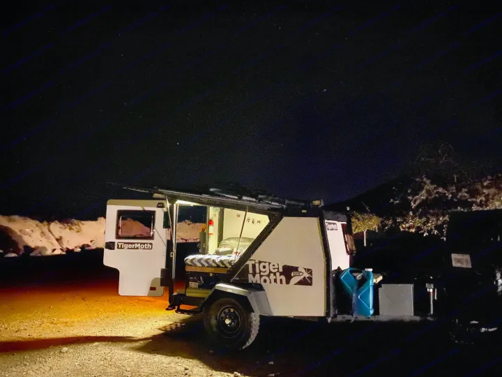 TigerMoth camper trailer open at night under a starry sky. Bed visible inside. Perfect for your next rv rental adventure.. TAXA Outdoors Tigermoth Camper 2021