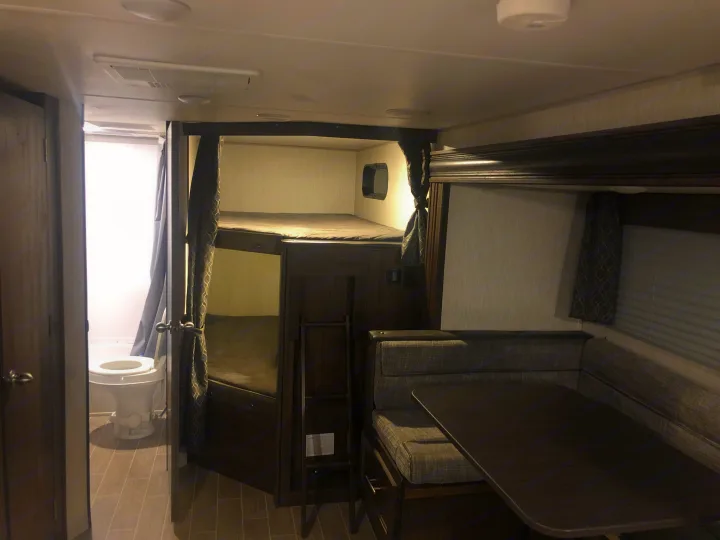 Interior of an RV rental with bunk beds, a dinette area, and a compact bathroom. Features practical living space.. Forest River Cherokee Grey Wolf 2020