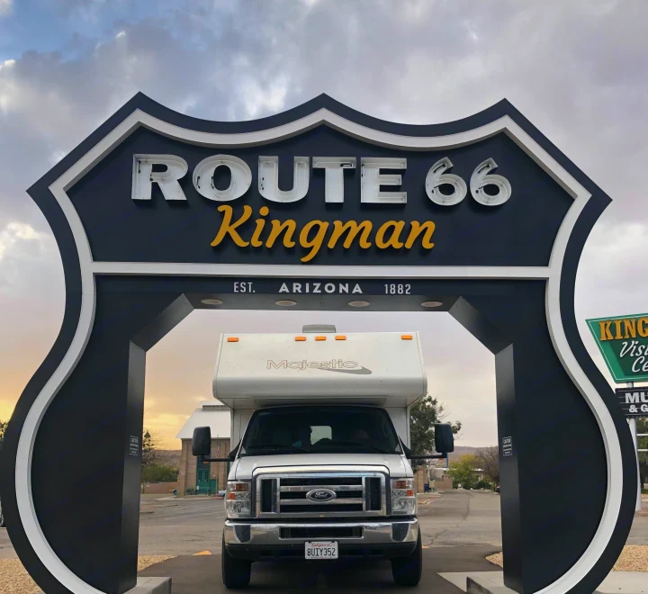 Front view of an RV rental under the large black and white Route 66 Kingman archway in Arizona. Ready for adventure!. Thor Motor Coach Four Winds Majestic 2017