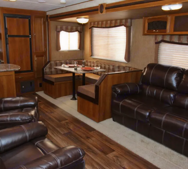 Spacious rv rental interior featuring a dining booth, kitchen area, and comfy brown leather sofas for a relaxing stay.. Forest River Avenger 28RKS 2015