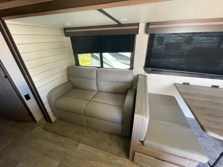 RV rental interior featuring a gray sofa, dinette bench, and wood-look flooring. Comfort for your road trips.. Crossroads RV Sunset Trail Super Lite 2021