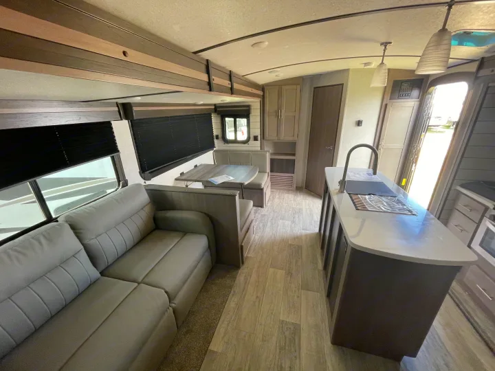 Spacious modern RV rental interior featuring a comfy living area, dinette, and well-equipped kitchen island.. Crossroads RV Sunset Trail Super Lite 2021