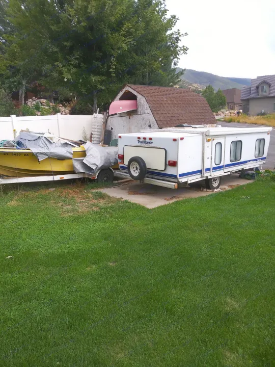 Yellow boat, white TrailManor RV, and pink canoe stored outdoors. Perfect for considering your next RV rental adventure.. K-Z Manufacturing Coyote 2002