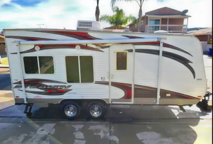 This white Stealth travel trailer RV rental, featuring red and black graphics, parked and ready for adventure!. Forest River Stealth 2012