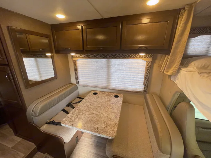 This RV rental features a functional dinette with a table and benches, ample overhead cabinets, and an integrated bed near the cab.. Chevrolet Other 2018