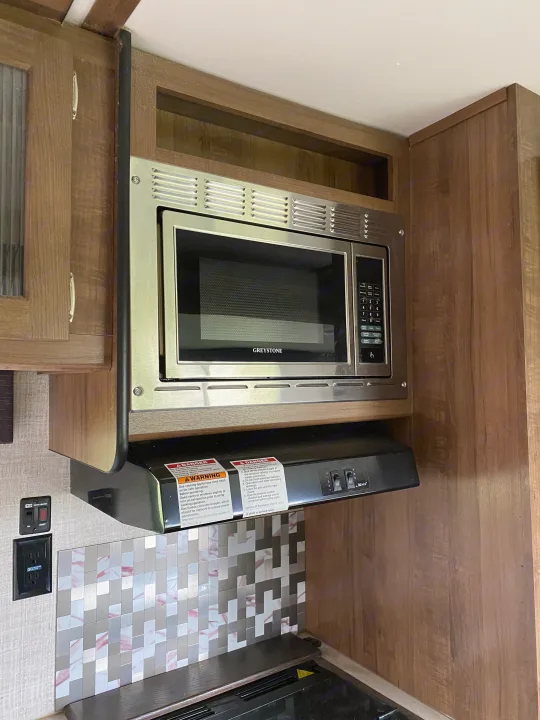 RV rental: Greystone microwave, range hood, and tile backsplash in a compact RV kitchen setup.. Gulf Stream Trailmaster 2020