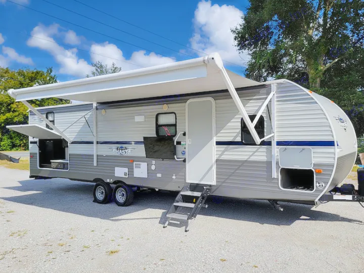 This grey travel trailer with an extended awning, open outdoor kitchen, and steps is available for rv rental.. Other Other 2021