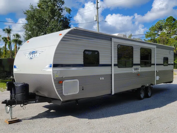 Spacious gray & white Shasta travel trailer, perfect for an RV rental. Parked outdoors on asphalt under a sunny sky.. Other Other 2021