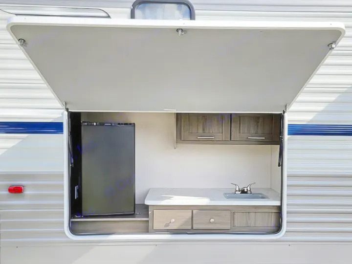 An RV rental's open side hatch reveals a full outdoor kitchen with a mini-fridge, sink, and storage.. Other Other 2021