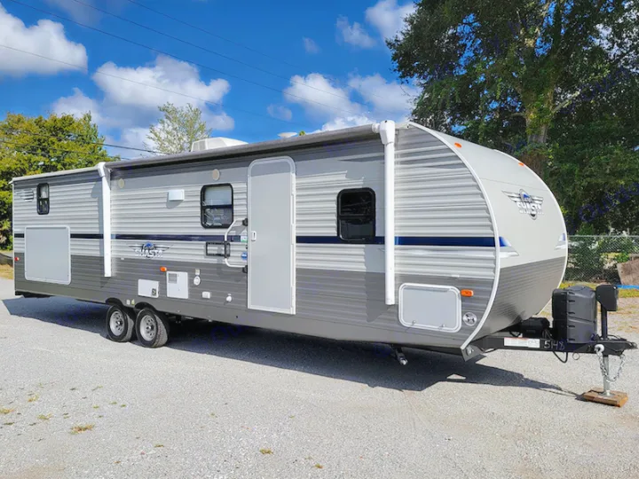 This gray travel trailer RV rental is parked outdoors on gravel, ready for adventure.. Other Other 2021