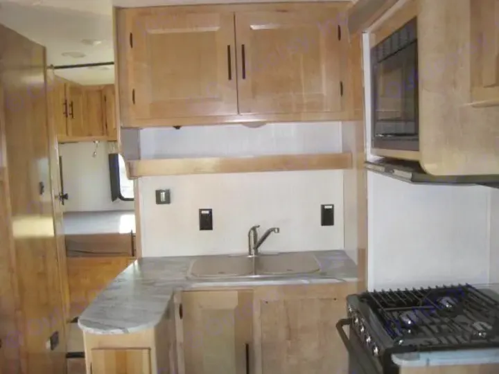 Spacious RV rental kitchen with light wood cabinets, microwave, sink, and gas stove. Perfect for your next adventure.. Coachmen Leprechaun 2021