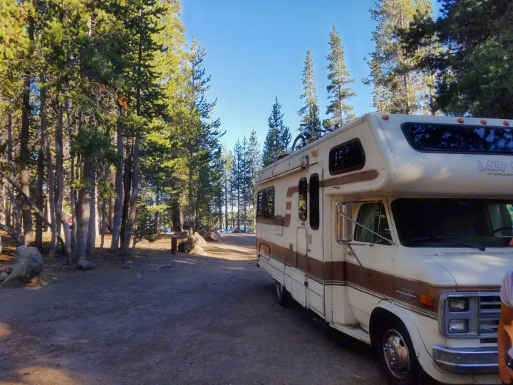 RV rental parked in a beautiful forest campsite near a lake. Perfect for nature adventures!. Lazy Daze 22 1987