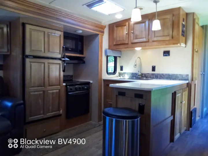 Spacious RV rental kitchen with modern appliances: fridge, microwave, stove, and ample cabinets. Ideal for comfortable travel.. Forest River Rockwood Ultra Lite 2018