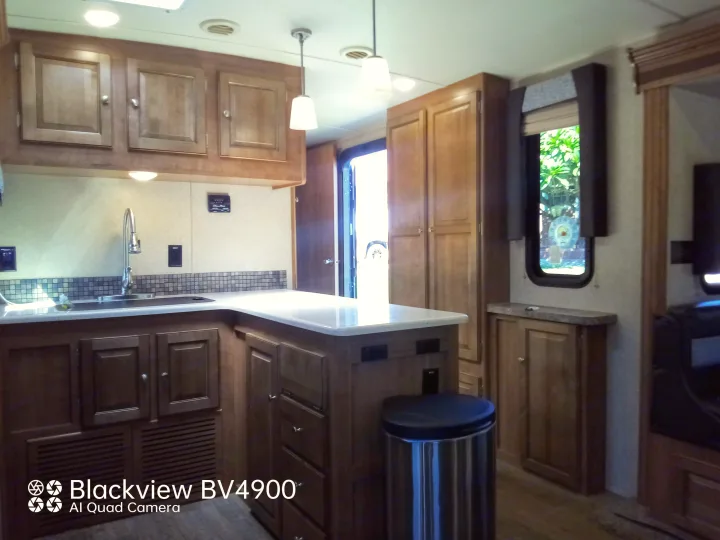 RV rental interior: Well-equipped kitchen with wood cabinets, sink, and countertop space, perfect for your travel needs.. Forest River Rockwood Ultra Lite 2018