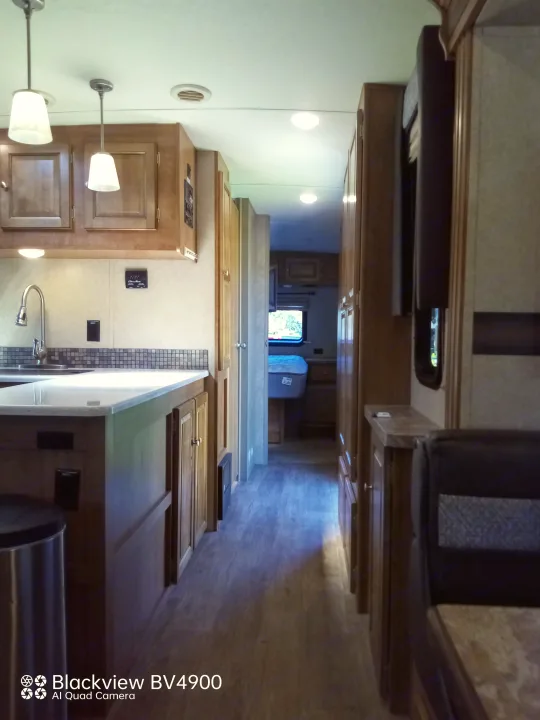 Spacious RV rental interior with kitchen, hallway, and bedroom visible, featuring wood cabinets and modern fixtures.. Forest River Rockwood Ultra Lite 2018